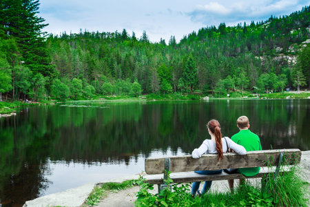 Romantic couple on a bench by the mountaine lakeの写真素材