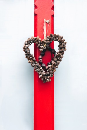 Wicker heart tied with a red ribbon to an old doorの写真素材
