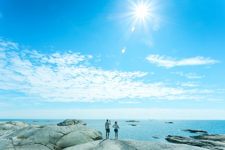 Romantic loving couple posing on stones near sea, blue skyの写真素材