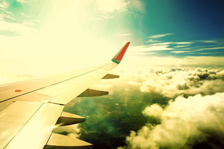 Airplane flying above clouds at sunriseの写真素材