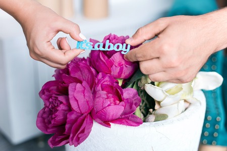 Happy couple expecting a baby: holding wooden sign it's a boy in handの写真素材
