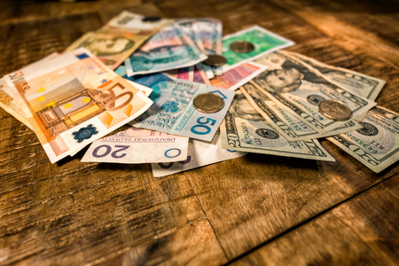 paper money of different denominations and different countries spread out on the tableの写真素材