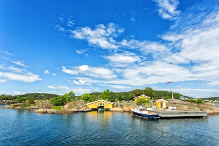 Beautiful wood holiday house cabin on the seafront during a sunny day in Norwayの写真素材