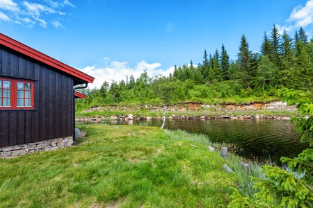 Wooden house in the forest above the lake in Norwayの写真素材
