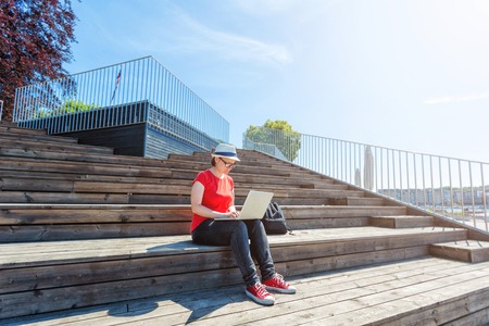 Young woman working as a freelance in a park with wooden stairsの写真素材