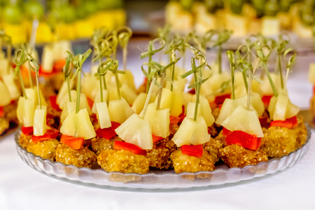 Catering service plate. Appetizing sandwiches on plastic sticks range. Sandwiches on a table the buffet. meat, fish, vegetable canapes on a festive wedding table outdoorの写真素材