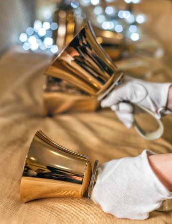 Jingle bells. Close-up of girl holding metal bell in hand and against light backgroundの写真素材