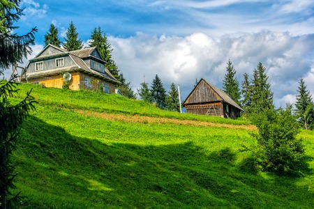 Traditional wooden mountain house on green field in summer, Ukraineの写真素材