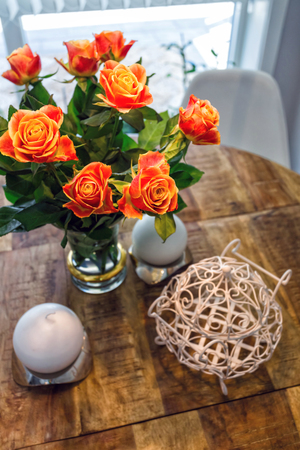 Beautiful roses in vase on wooden table on brown backgroundの写真素材