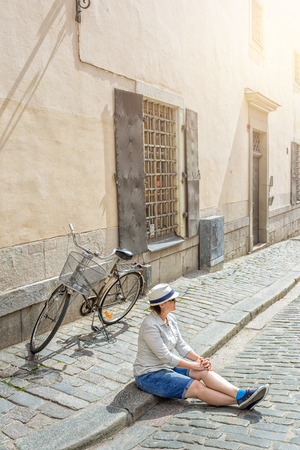 Young female traveler sitting with bicycle on the street in Stockholm, Sweedenの写真素材