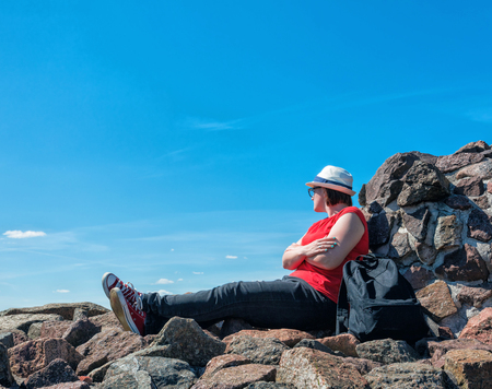 Young tourist woman is feeling free and sitting on the top of the mounting and looking at a beautiful landscapeの写真素材