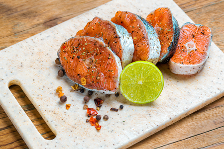 Raw marinated trout fillet on wooden cutting board. Steak of salmon ready to fryingの写真素材
