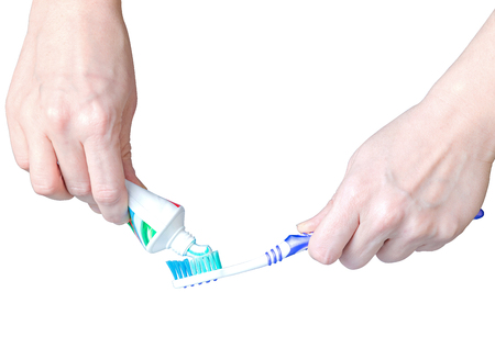 Toothpaste and a brush in a mans hand isolated on whiteの写真素材
