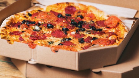 Italian pizza in cardboard box on wooden table. Top viewの写真素材