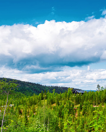 Landscape with old wooden houses and mountains covered by cloudsの写真素材