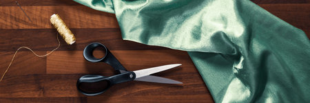 shears gold thread and satin blue textile on the wooden table