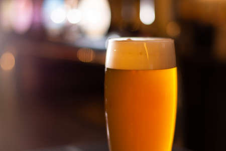 a glass of craft beer lager golden color on blurred backgroundの写真素材