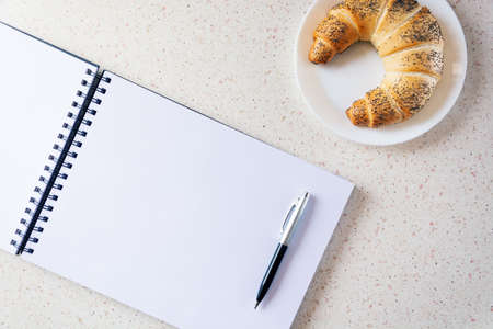 table with empty notebook and plate with twirl home office study at home tableの写真素材
