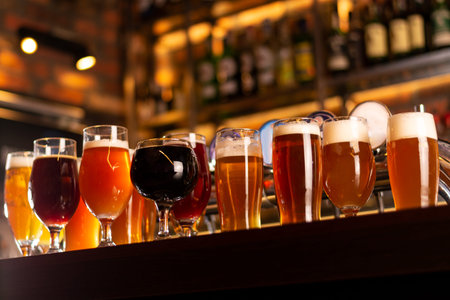a lot of craft golden beer on bar table in worm lights and blurred background