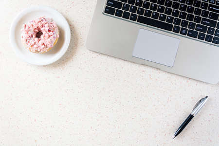 donut on plate laptop and pen on the table home office remote workingの写真素材