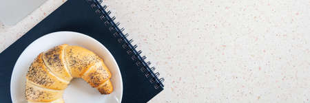 desktop with laptop keyboard and pen and plate with croissant horizontal, panorama, panoramicの写真素材