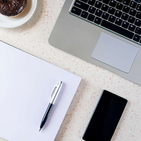 top of desk with notebook pen smartphone plate with donut and laptop keyboard square, cube, quadの写真素材