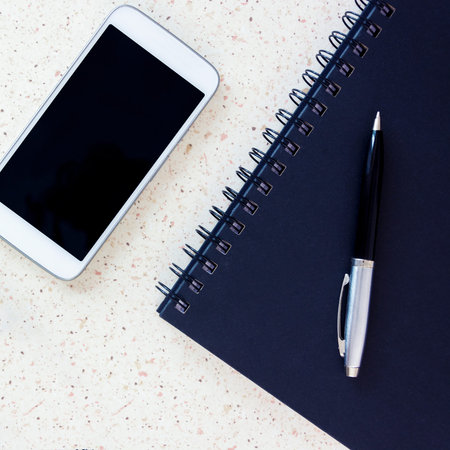 top of the office desk with smartphone blue notebook pen square, cube, quad