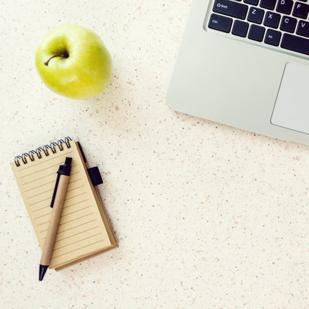 top of desk with notebook pen green apple and laptop keyboard square, cubeの写真素材
