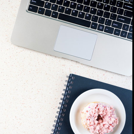 pink donut and pen on the table with laptop cube, square