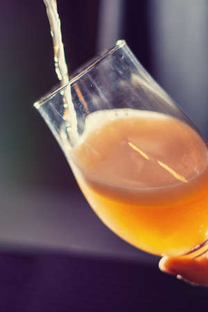 pouring fruit craft beer in to the glass close up on blurred backgroundの写真素材