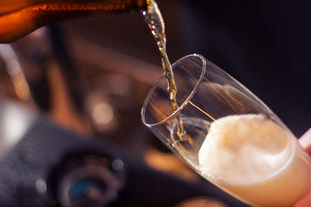 bartender pouring craft beer in to the glass on blurred backgroundの写真素材
