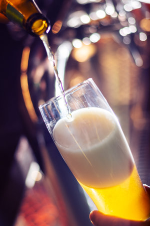bartender pouring craft beer to glass close up on blurred background