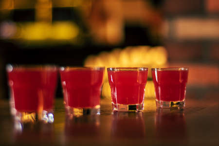 red vodka shots on wooden table close up on wooden tableの写真素材