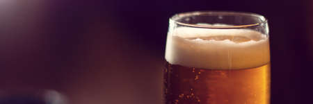 glass of beer close up on wooden table panoramaの写真素材