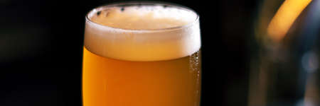 glass from light craft beer on wooden table panoramaの写真素材