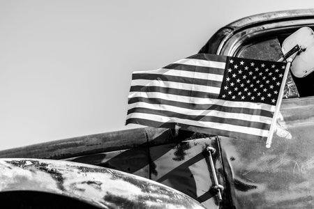American flag on an old car. Close-up. Black and white.