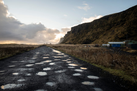 Icelandic landscape with asphalt road and dramatic sky at sunrise.