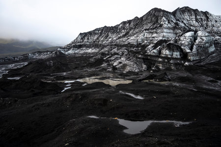 Icelandic landscape with black volcanic rocks and a lake in the foregroundの写真素材