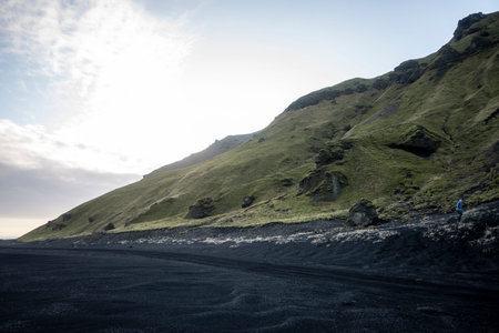 travel to Iceland - man walking on Reynisfjara black sand beach near Vik I Myrdal village in...