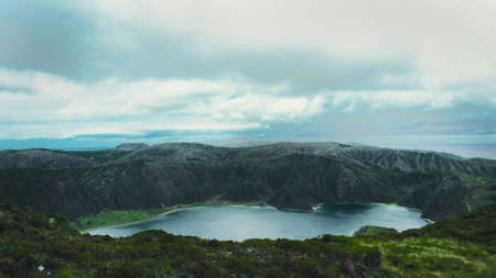 Mountain view on Caldeira do Siete Cidades - crater with green slopes, blue water lake and cloudy blue sky on Sao Miguel Island, Azores, Portugal. The scene is quiet, peaceful and allow on relaxing.の写真素材