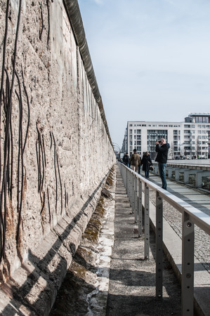 Last remains of the Berlin wall along the ex headquarters of the Gestapo and the SS in Niederkirchnerstrasse 8. the picture people watching wall.のeditorial素材