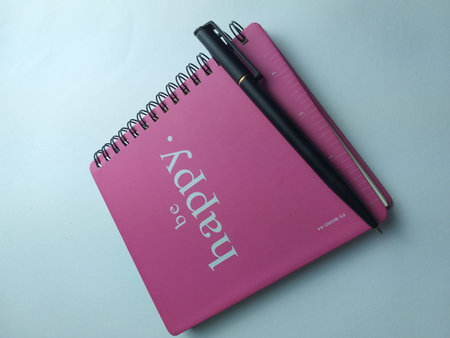 Notebook and pen on blue background. Top view with copy space.