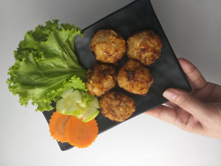 crispy fried meatballs with lettuce and carrot on black plateの写真素材