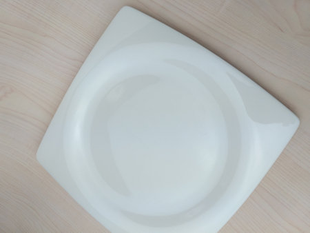 White ceramic plate on wooden table. Top view. Copy space.の写真素材