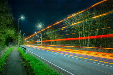 Light trails at urban road created by lights from truck and cars. Colorful, orange, red and white star shape from light post.の写真素材