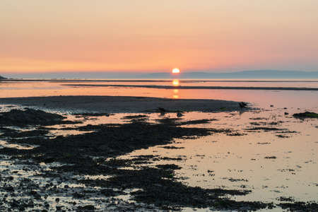 Sunset reflection mirror over the beach horizontal line, colorful shading sky, peaceful mind.の写真素材