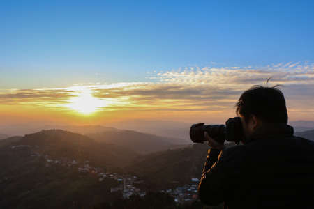 Silhouette of a photographer at sunrise time - photographer taking a landscape pictureの写真素材