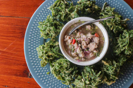 Vegetable fritters serve with spicy minced pork salad in wooden table - Thaifoodの写真素材