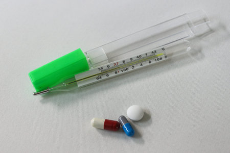 Close-up various pills and thermometer on white background
