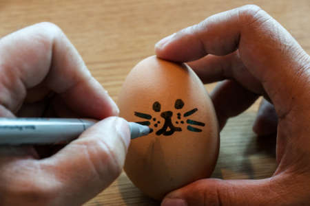 Child hand drawing easter egg with pen on woonden tableの写真素材